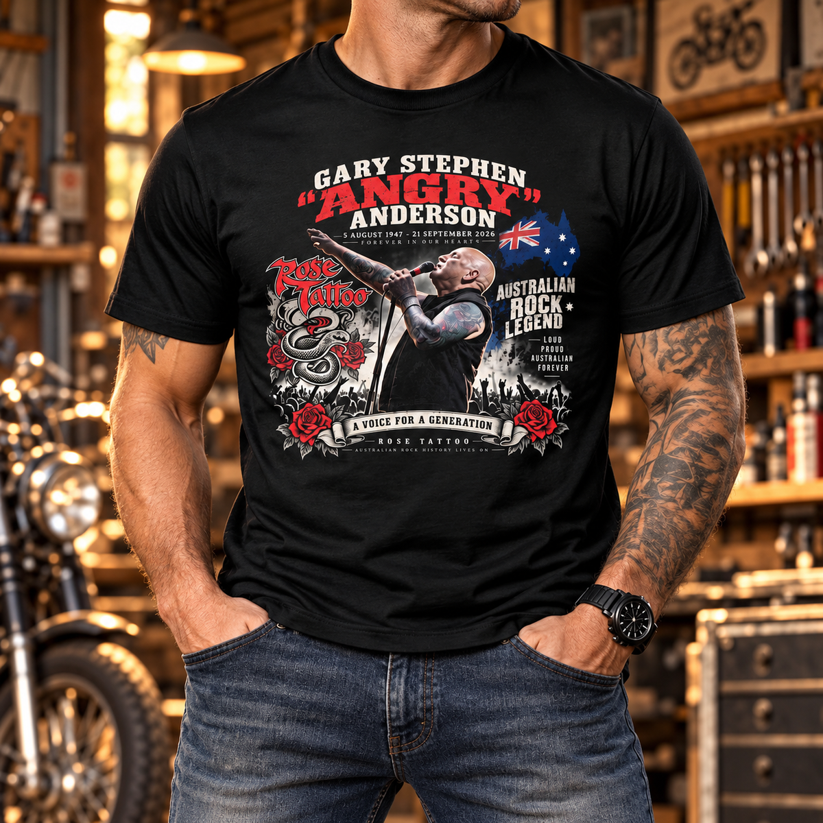 Man wearing the black Angry Anderson tribute front-print T-shirt in a warm vintage motorcycle workshop