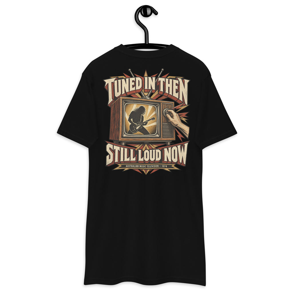 Tuned In Then Still Loud Now Heavyweight Tee — Black, back view on hanger (Printful)