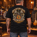 Man wearing the black Outlaw Slide and Blues T-shirt in a music venue, showing the guitar and amplifier back print