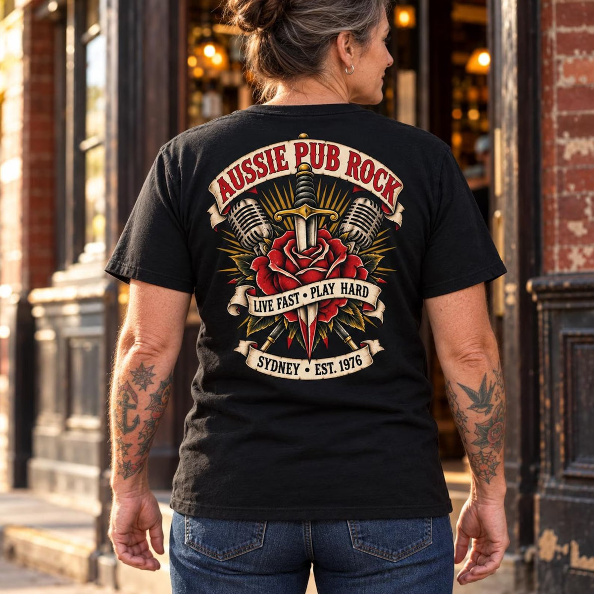 Woman wearing the black Australian Pub Rock T-shirt, showing the rose and dagger back print