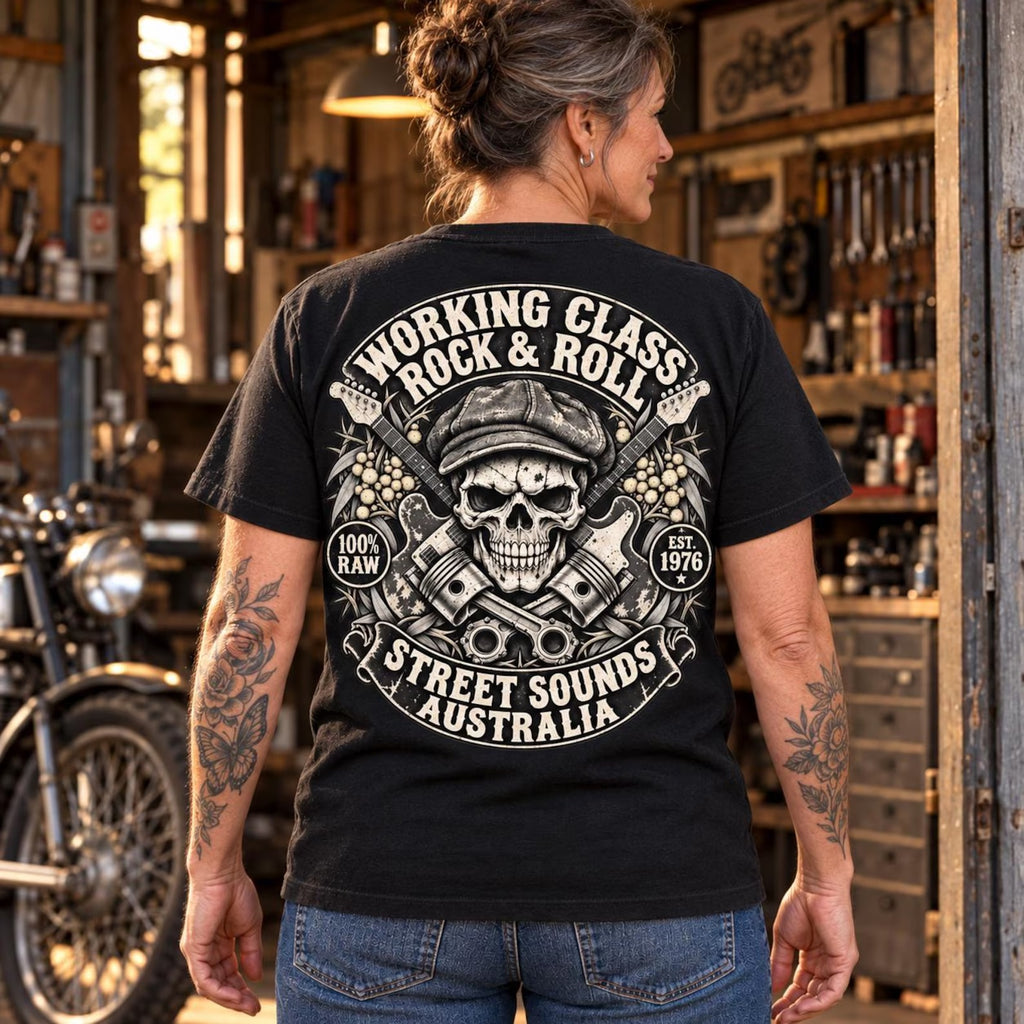 Woman wearing the black Working Class Rock and Roll T-shirt in a motorcycle workshop with the back print visible