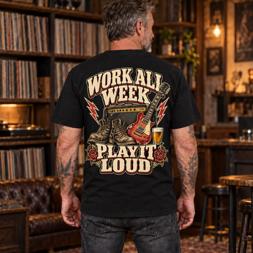 Mature tattooed man wearing the Work All Week Play It Loud black heavyweight tee, back print visible in a warm vinyl listening room